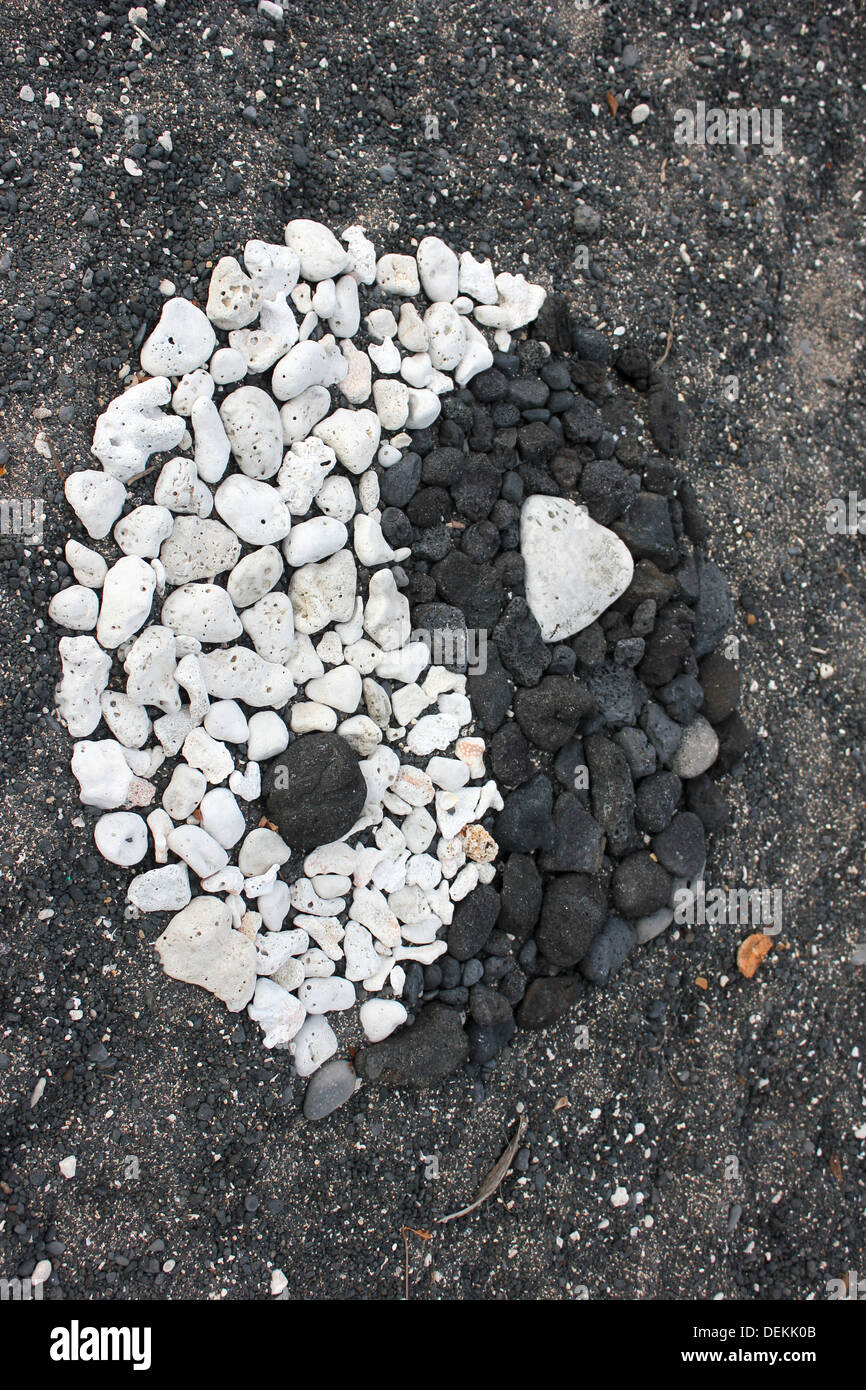 Yin Yang simbolo realizzato da corallo bianco e pietra lavica sulla spiaggia di sabbia nera in Hawaii Foto Stock