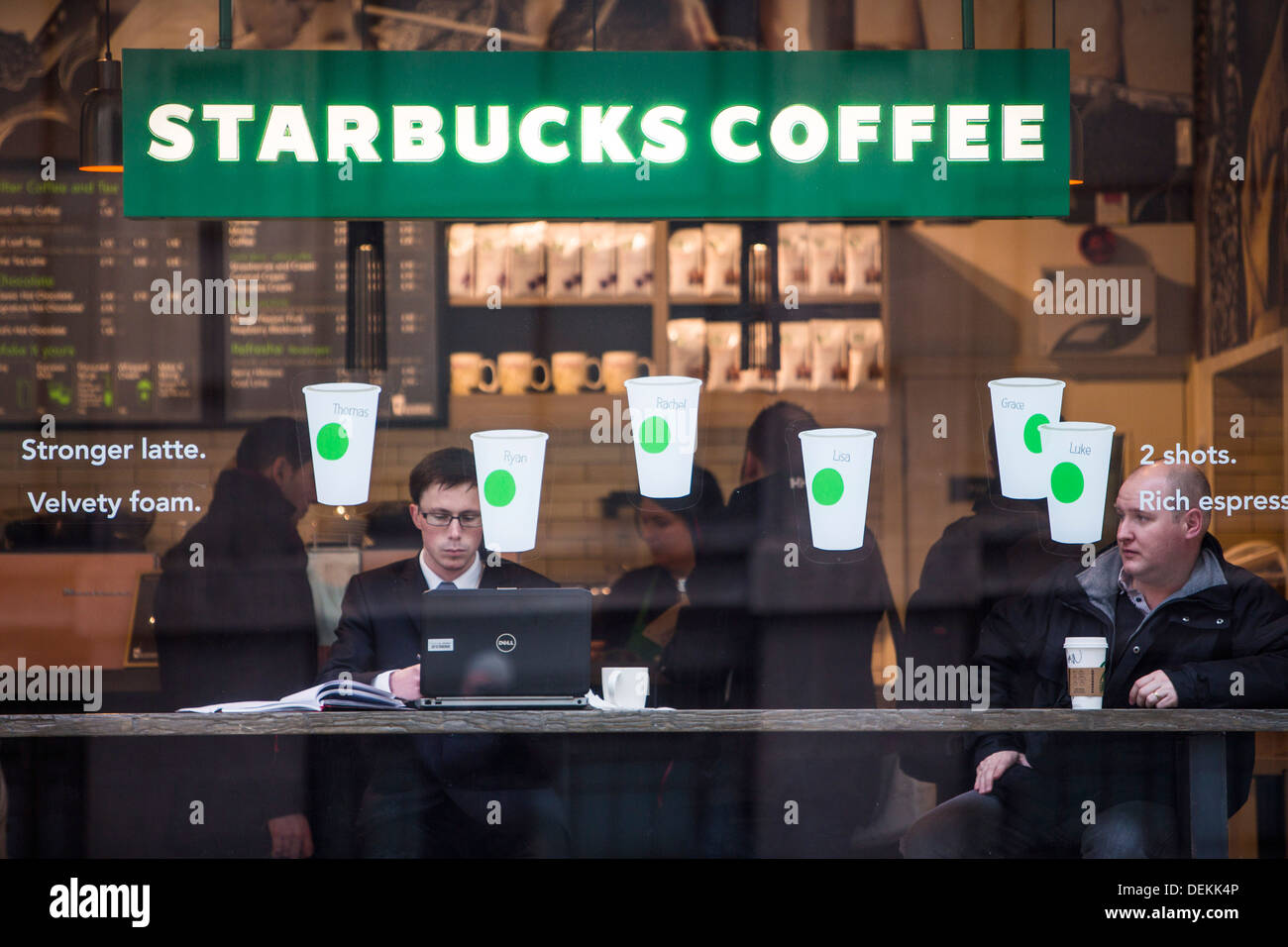 I clienti a bere il caffè nella finestra di un Starbucks Coffee shop nella città di Londra. Foto Stock