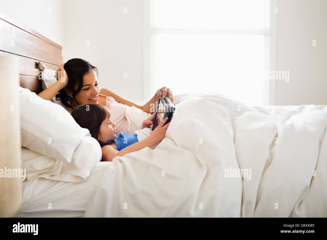 Madre e figlia con tavoletta digitale a letto Foto Stock