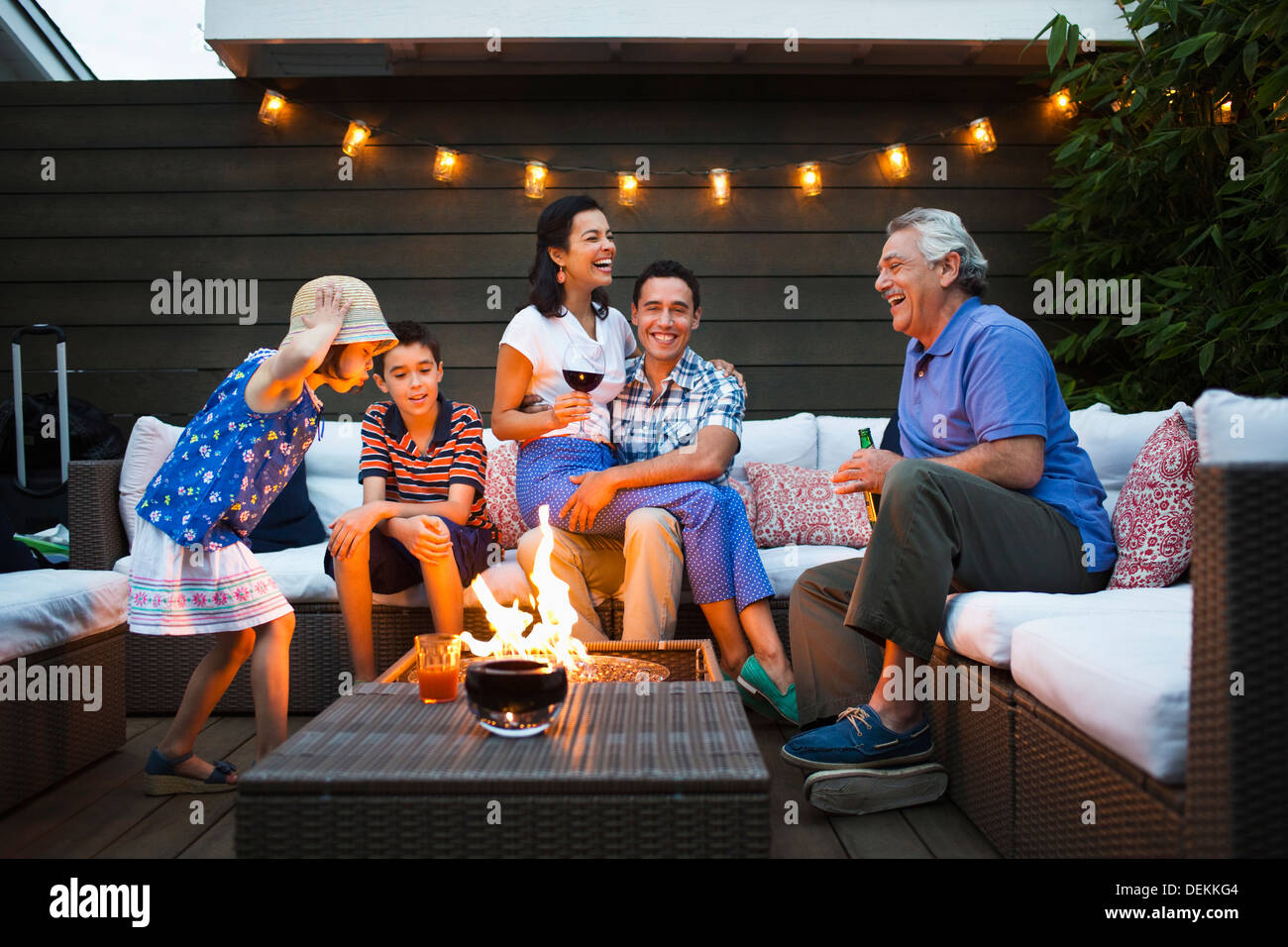 Famiglia relax intorno una buca per il fuoco all'aperto Foto Stock