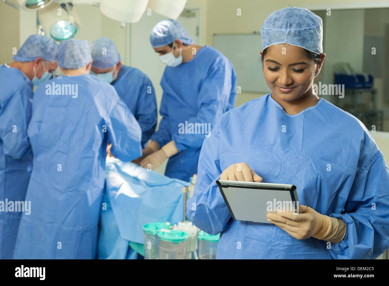 Femmina donna asiatica infermiere medico chirurgo utilizzando computer tablet con intervento chirurgico team in chirurgia ospedaliera teatro operativo Foto Stock