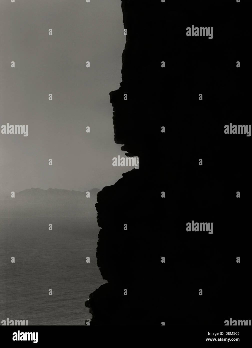 Sillhouette della rupe robusto per mare Foto Stock