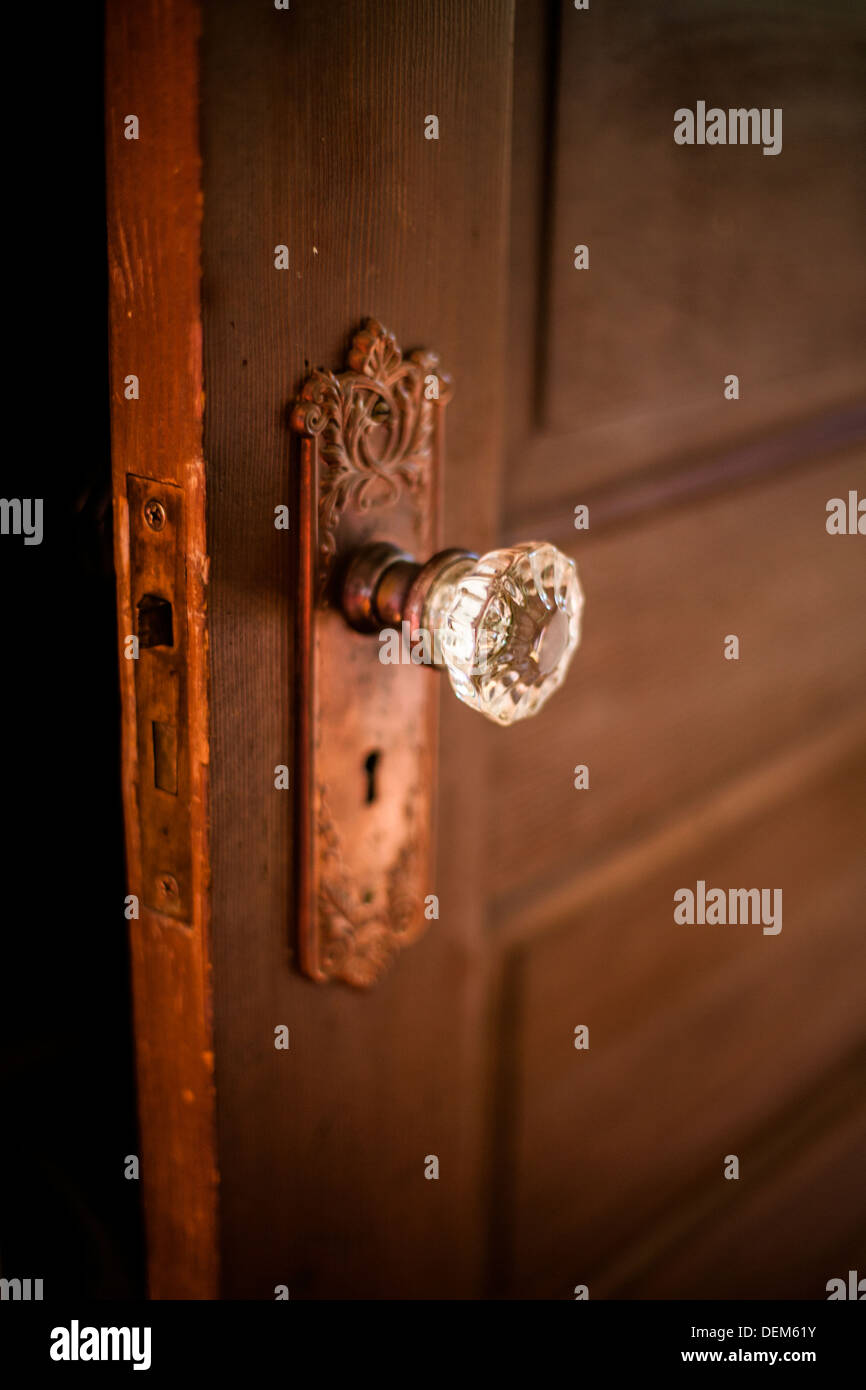 Primo piano di una antica porta di legno all'interno di una casa con una maniglia di vetro e lo scheletro di foro per la chiave. Foto Stock