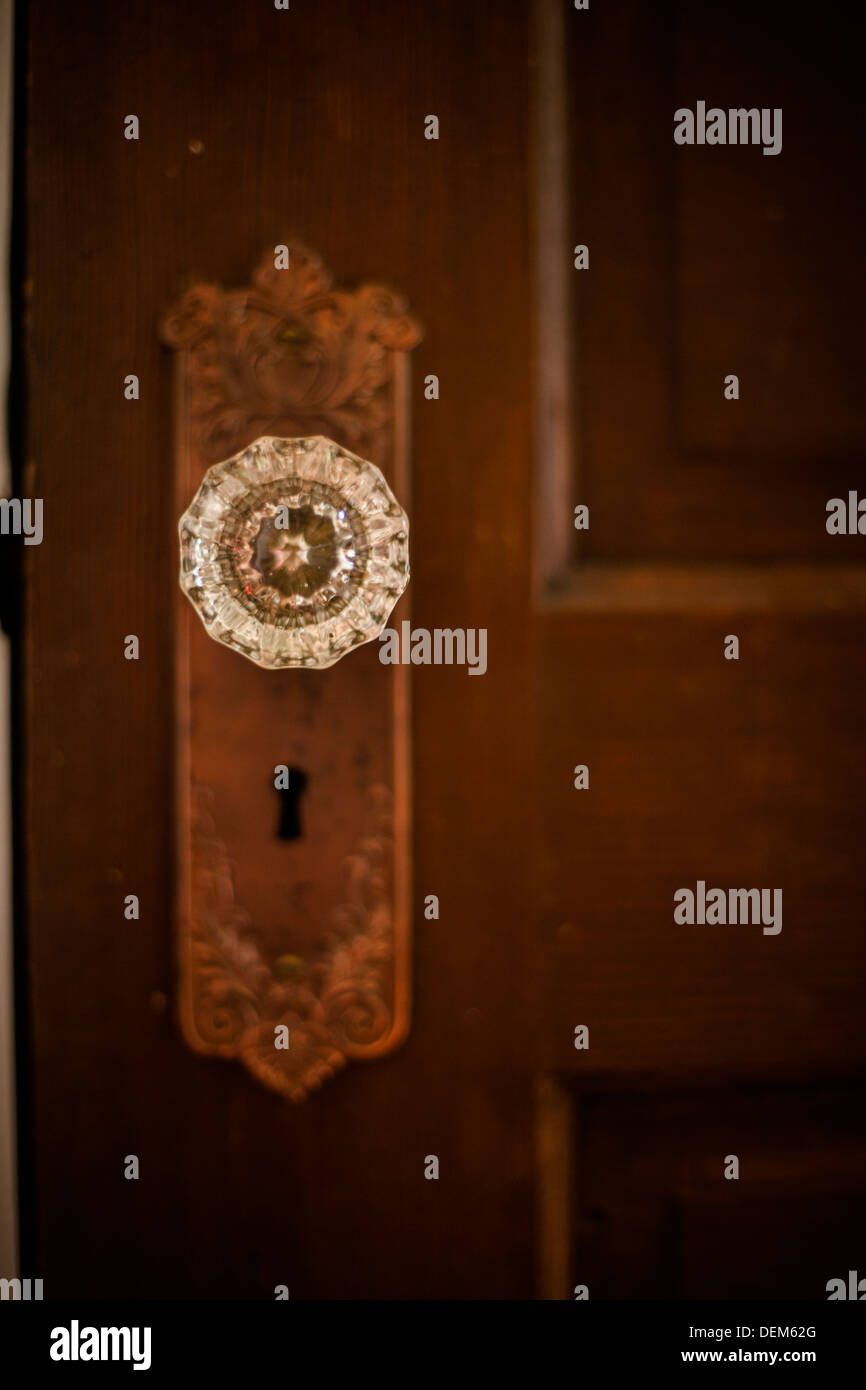 Primo piano di una antica porta di legno all'interno di una casa con una maniglia di vetro e lo scheletro di foro per la chiave. Foto Stock