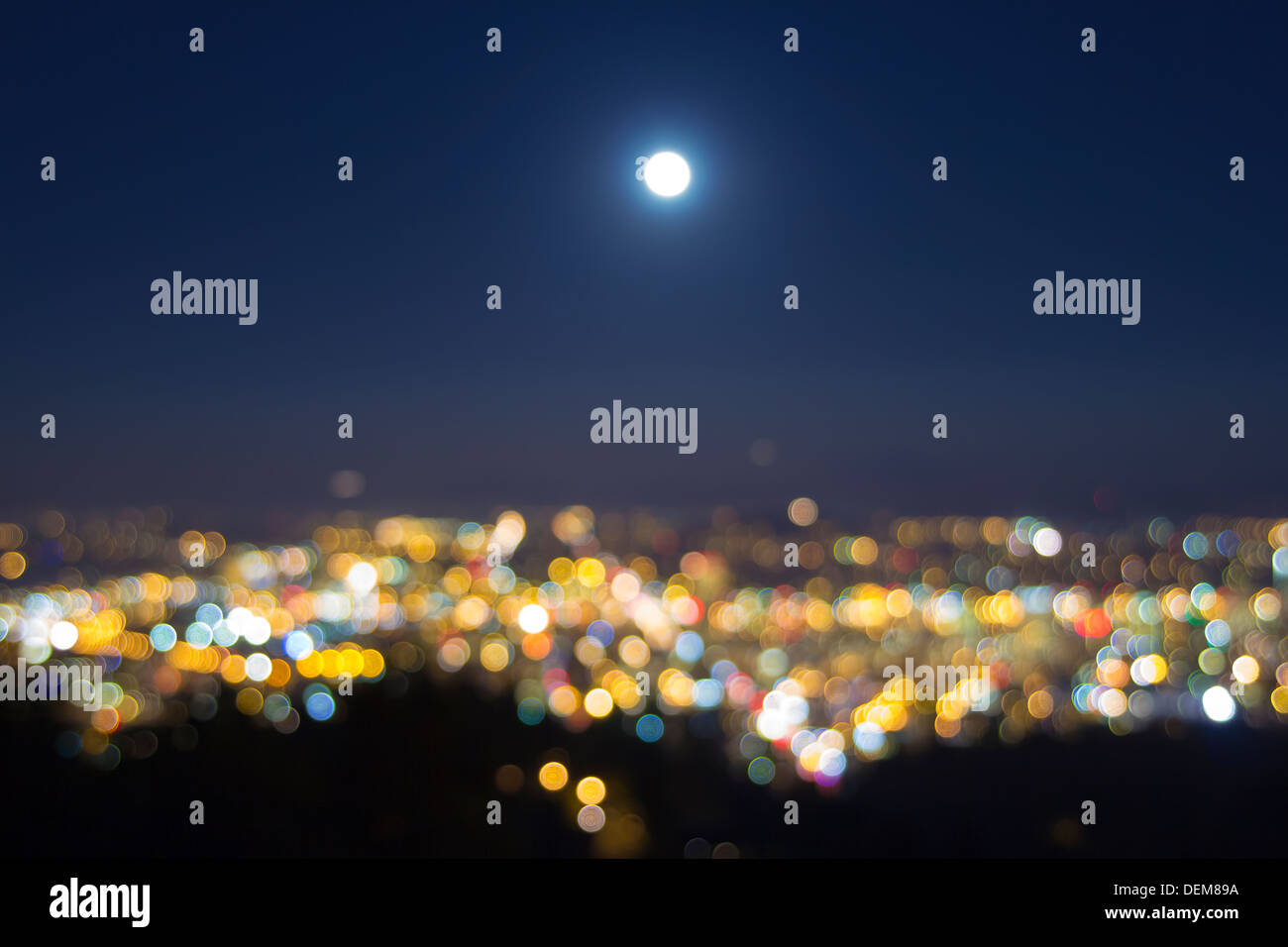 Harvest luna piena ascesa sopra sfocata città sfocati costruzione paesaggio luci alla sera ora blu Foto Stock