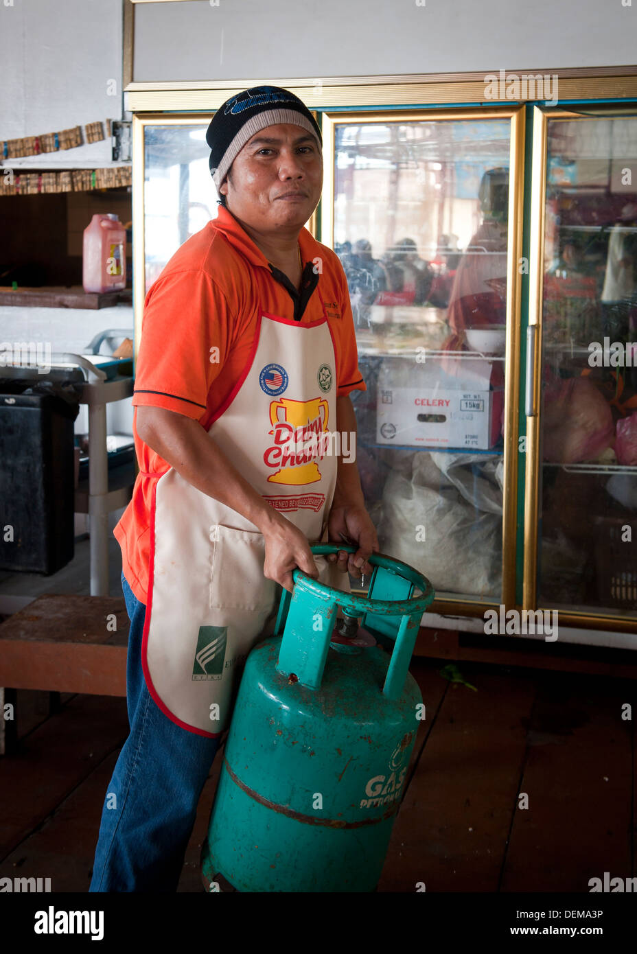 Uomo asiatico che trasportano gas pesante bottiglia nel ristorante. Foto Stock
