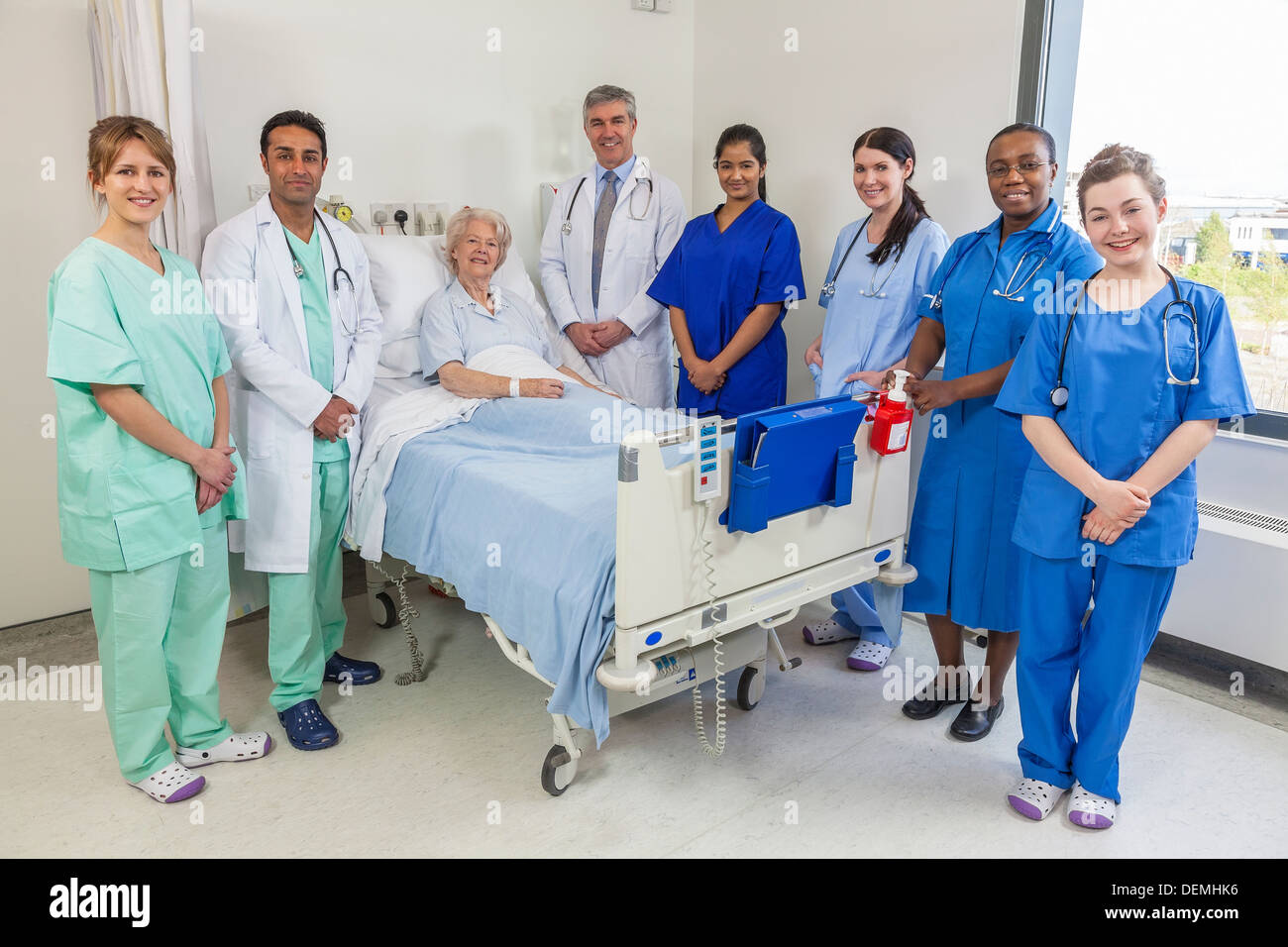 Senior donna femmina paziente letto di ospedale con multi etnico interracial team medico uomini donne femmine e maschi medici infermieri Foto Stock