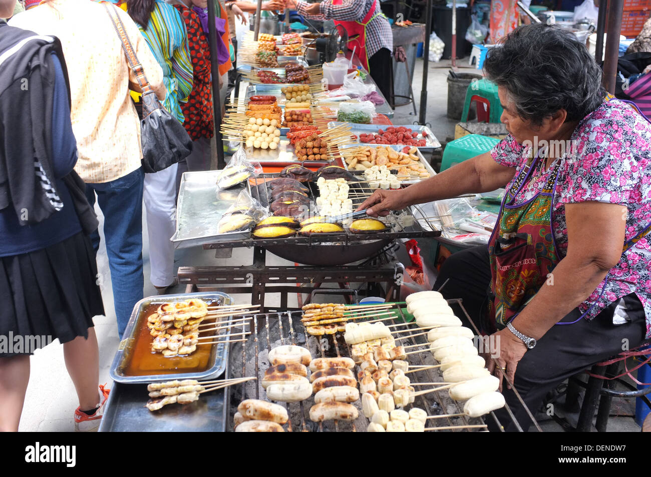 Donna grigliare le banane al mercato all'aperto in Bangkok Foto Stock