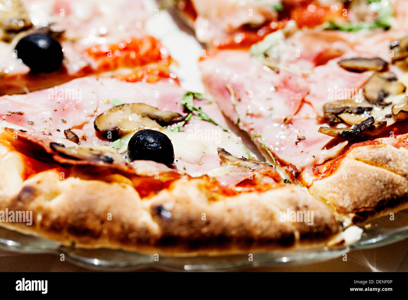 Pane appena sfornato la pizza con un prosciutto, funghi e olive topping servita all'aperto su una luminosa giornata di sole Foto Stock