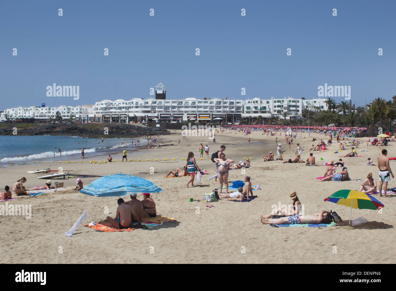 Turisti sulla sabbia a Playa de las Cucharas, Costa Teguise, Lanzarote, Isole Canarie, Spagna. Un popolare resort di Lanzarote Foto Stock