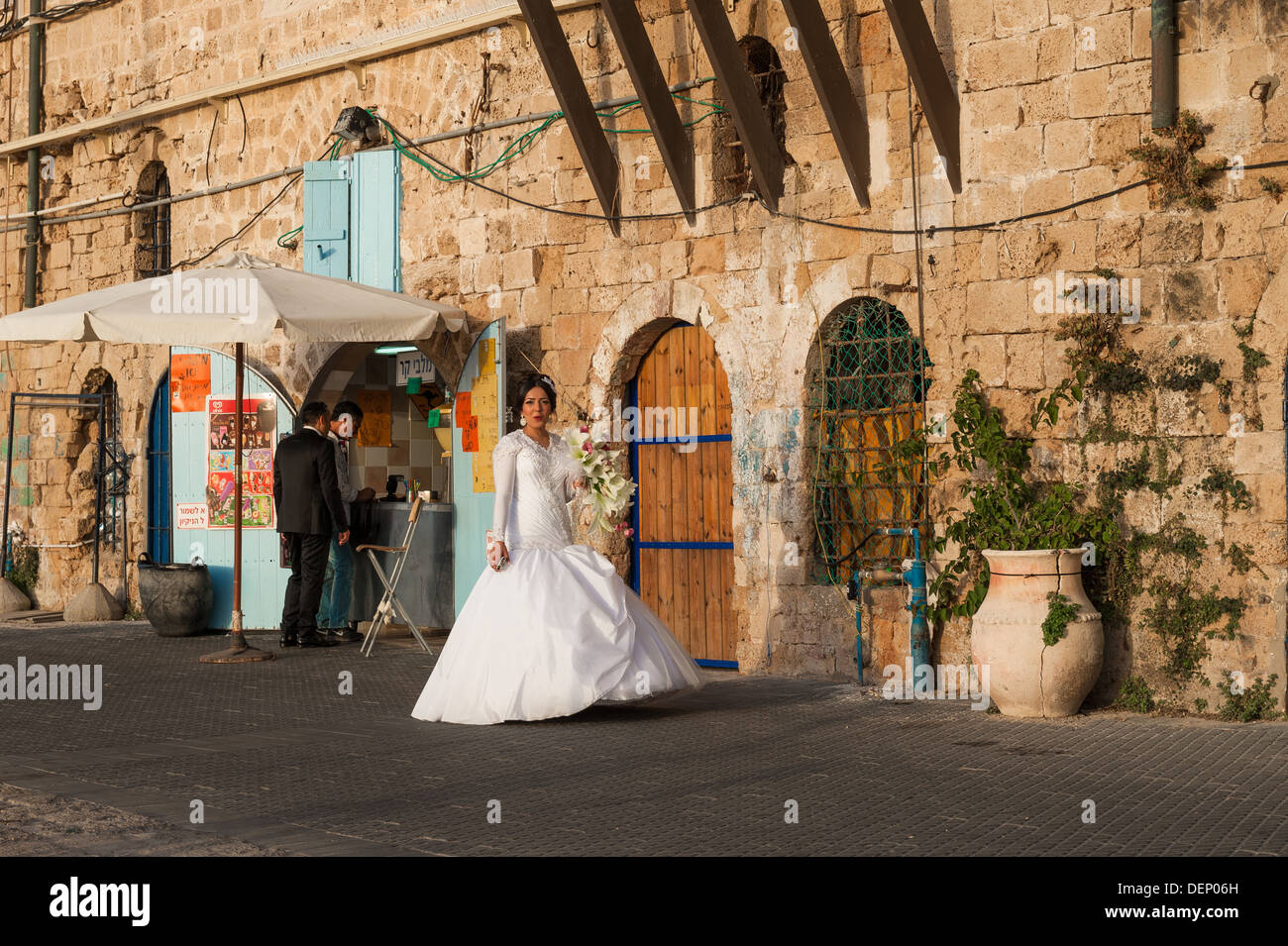 Una giovane coppia nel loro giorno delle nozze prendendo una breve pausa da fotografata al vecchio porto di Jaffa in Israele Foto Stock