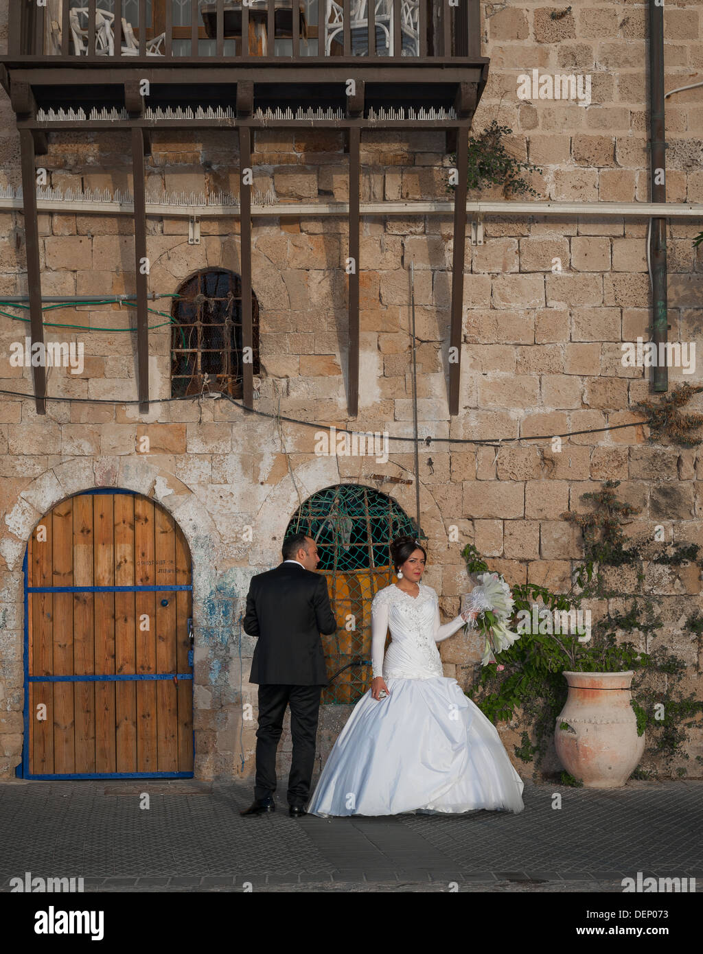 Una giovane coppia nel loro giorno delle nozze prendendo una breve pausa da fotografata al vecchio porto di Jaffa in Israele Foto Stock