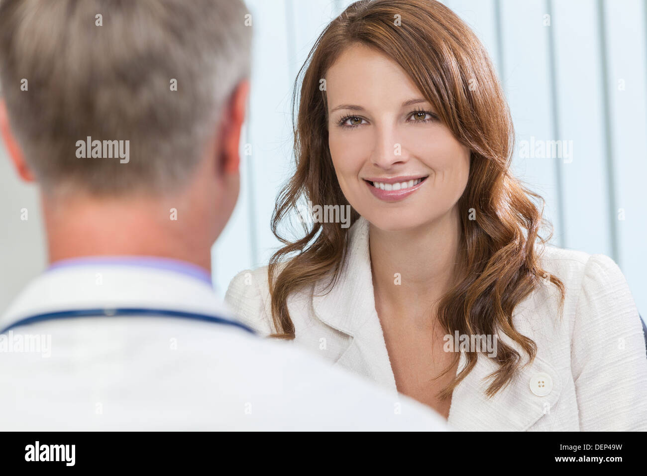 Sorridenti donna di mezza età paziente o collega riunione appuntamento per un colloquio di consulenza con connettore maschio di tipo medico ospedale ufficio di chirurgia Foto Stock
