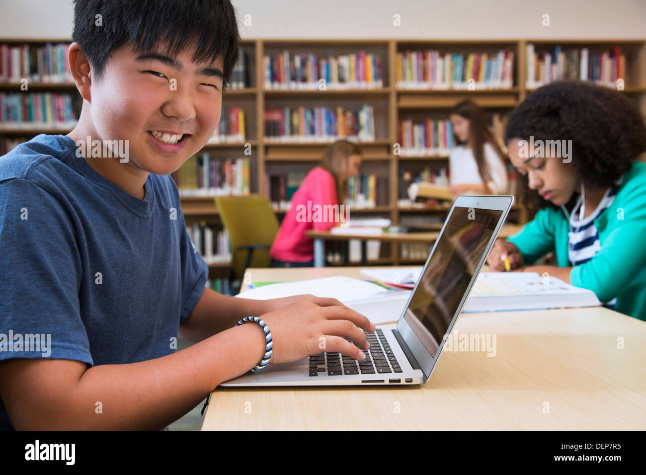 Studente utilizzando laptop in biblioteca Foto Stock
