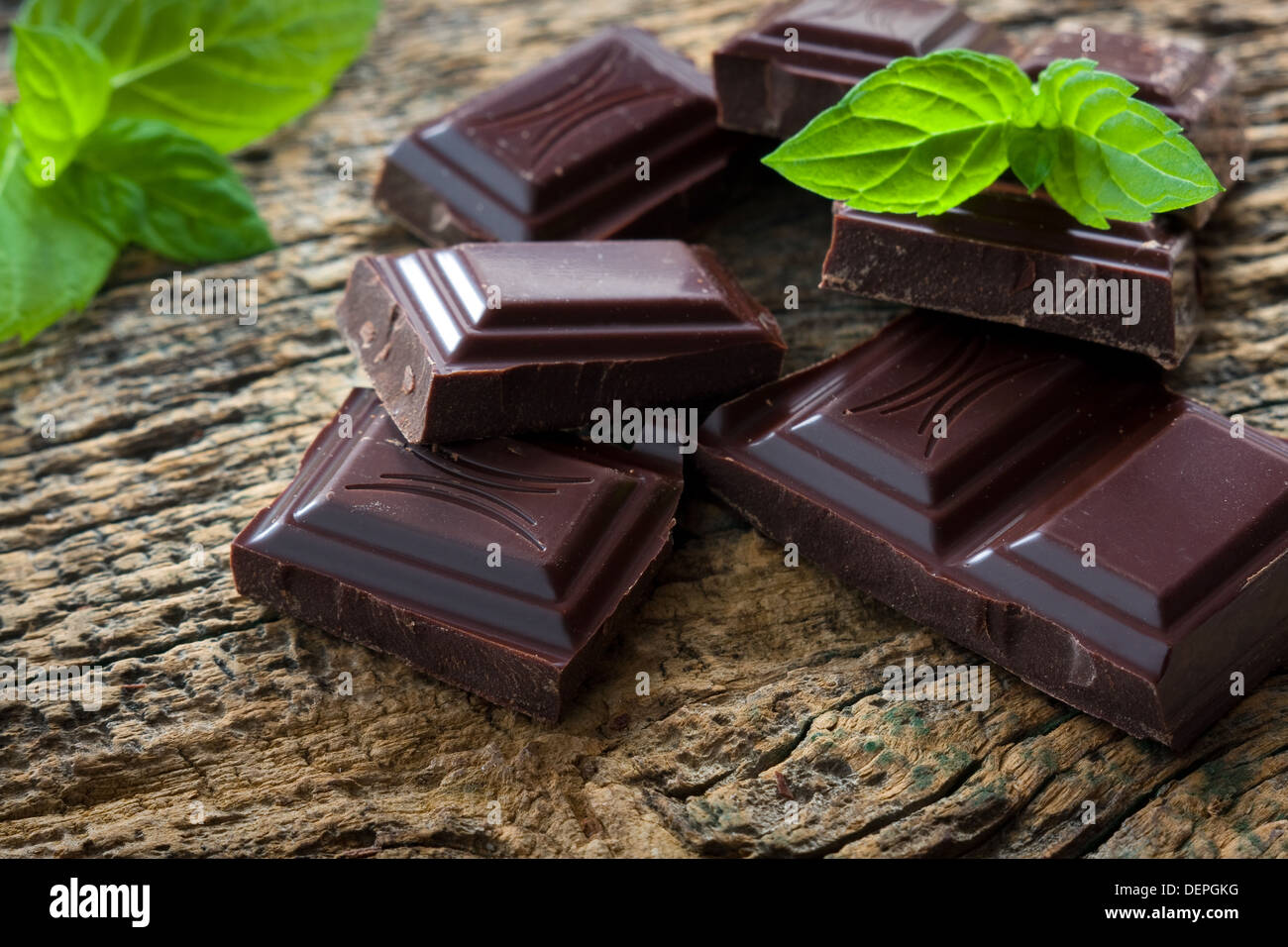 Cioccolato fondente di pezzi con una foglia di menta su sfondo di legno Foto Stock