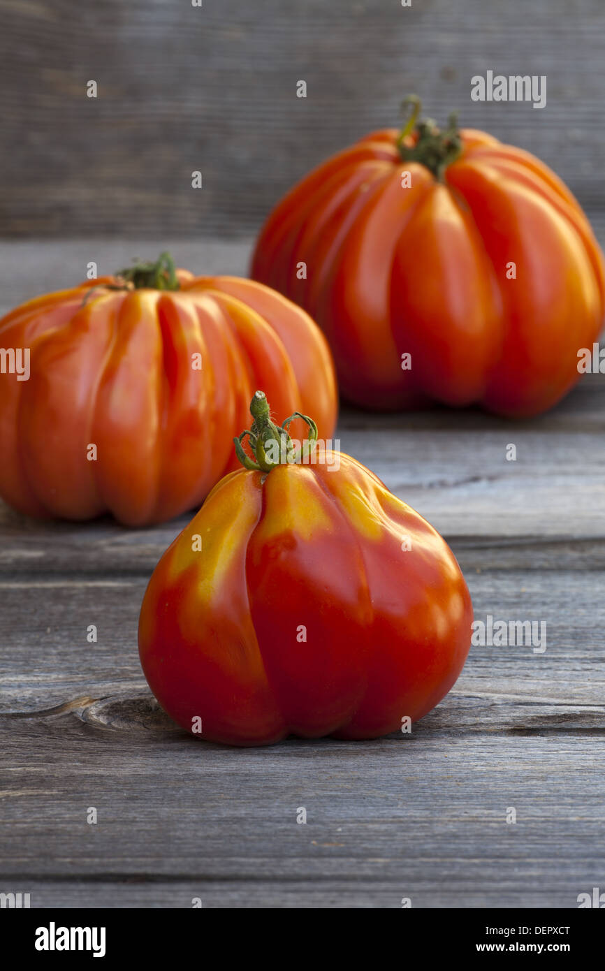 Tre grandi bistecca di manzo pomodori freschi dal mercato settimanale su un vecchio tavolo in legno Foto Stock