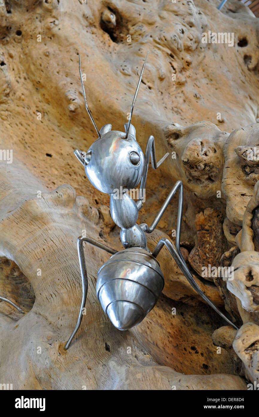 Grande in acciaio inossidabile replica di una formica su una corteccia inferiore tronco di albero. Foto Stock