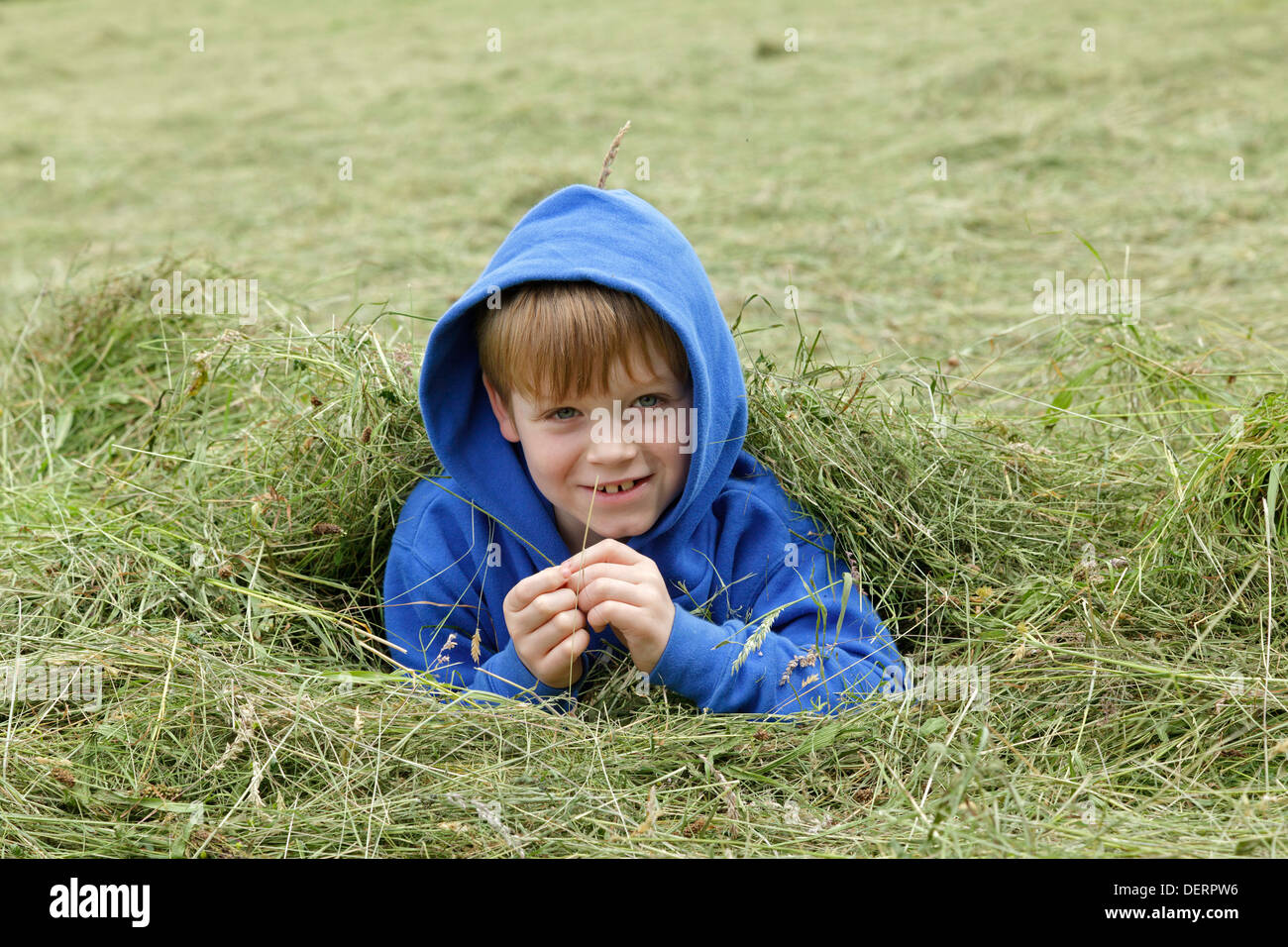 Giovane ragazzo giocando in un campo di fieno Foto Stock
