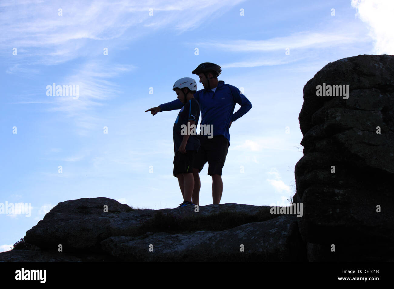 Silhouette di padre e figlio che indossa caschi ciclismo rivolta verso l. Foto Stock