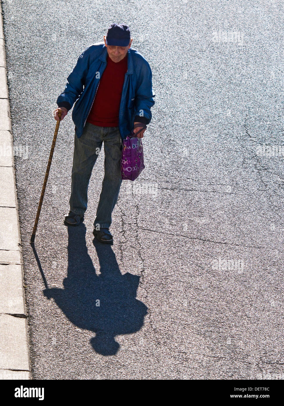Il vecchio uomo (da sopra) camminando lungo la strada + shadow - Francia. Foto Stock