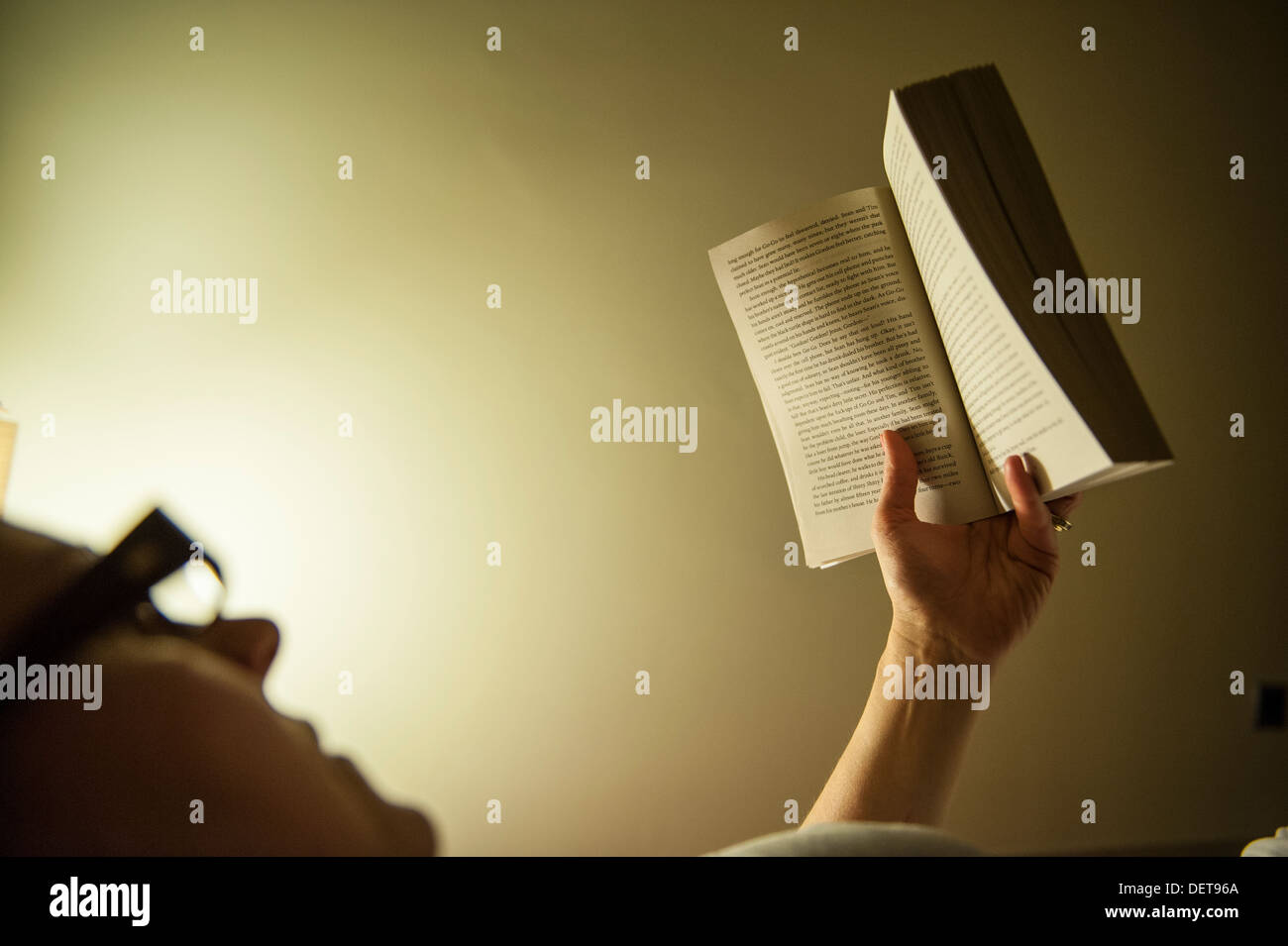 Una donna si legge nel letto di notte Foto Stock