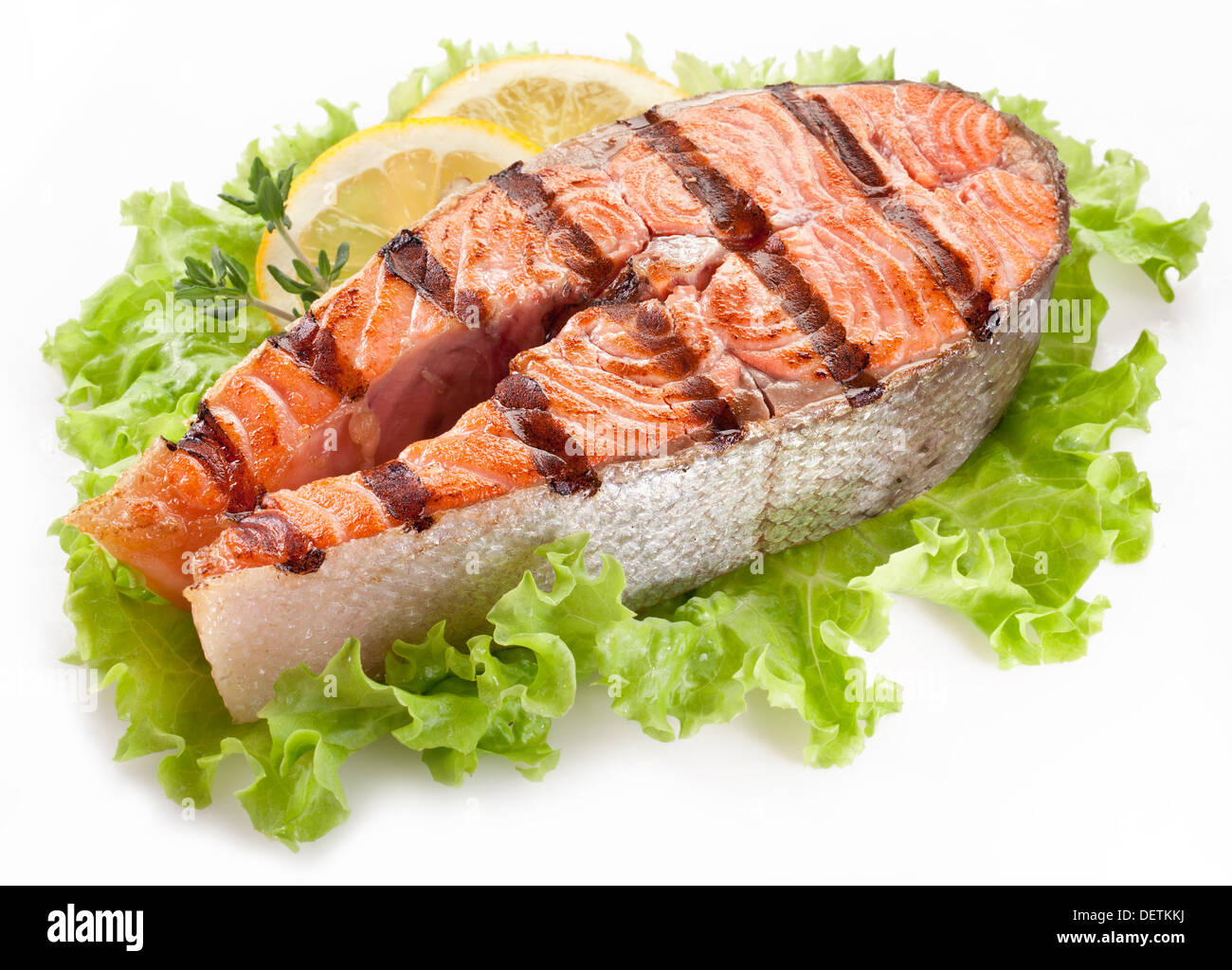 Salmone alla griglia con le fette di limone su foglie di lattuga. Studio isolato. Foto Stock