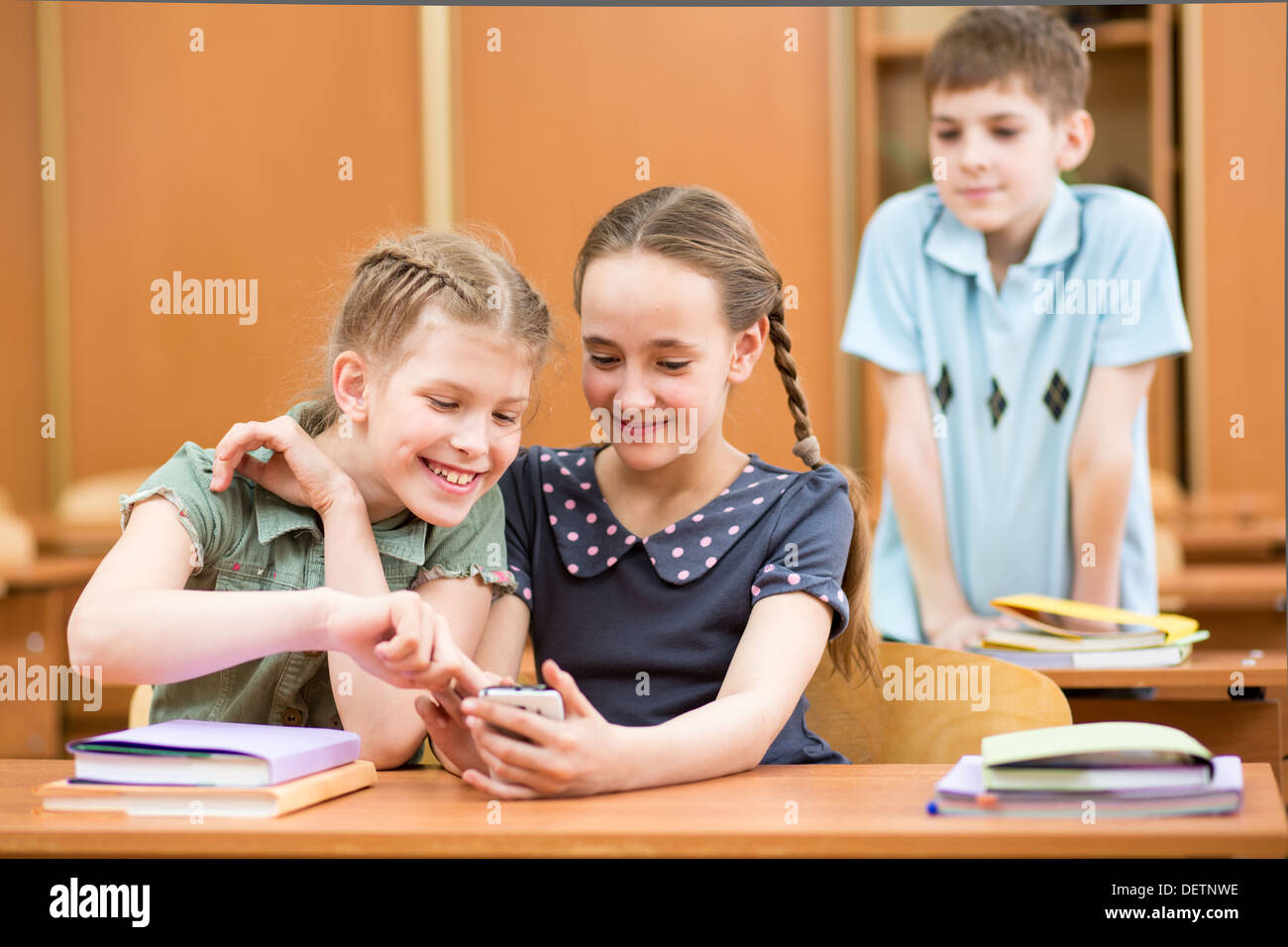 I bambini della scuola con i telefoni cellulari in aula Foto Stock