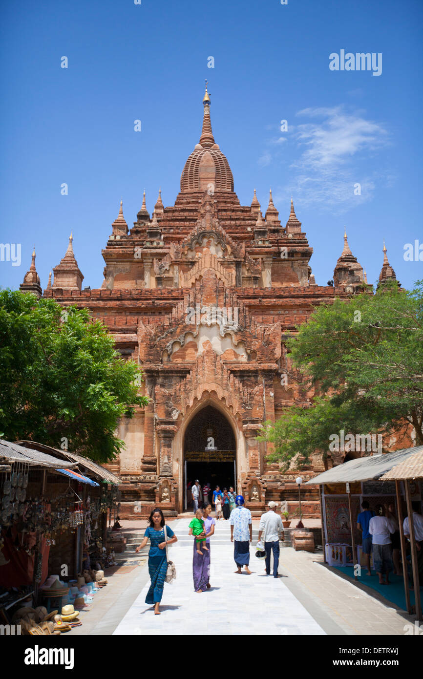 La gente a piedi al di fuori di un tempio nella pianura a nord di Bagan. Foto Stock