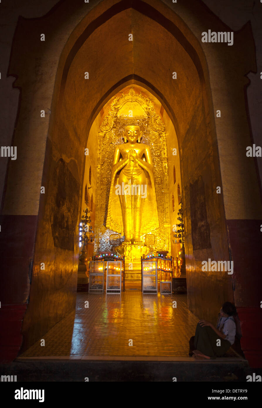 La gente a piedi passato a un'immagine del Buddha in un tempio di Bagan. Foto Stock