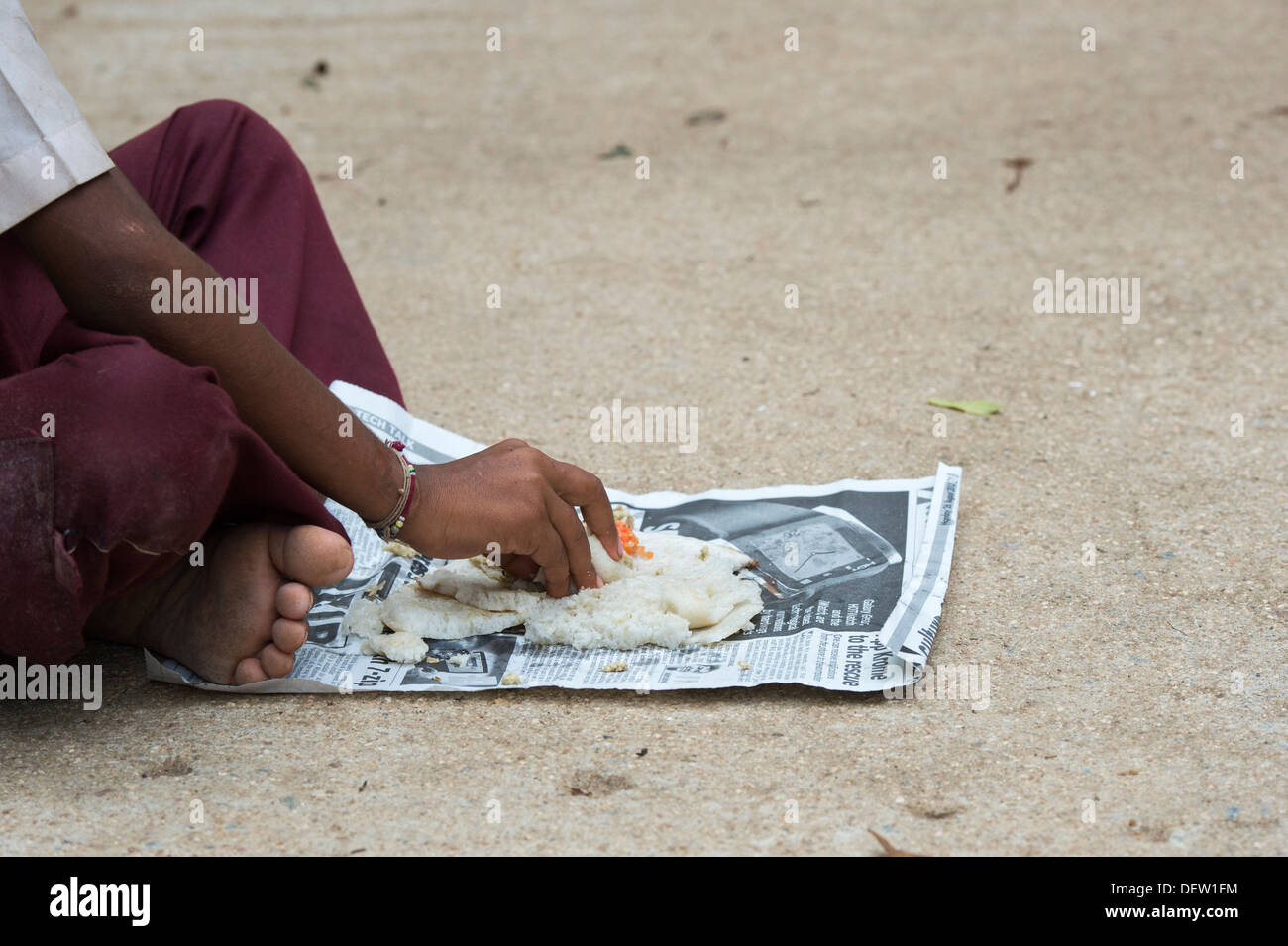 Indiano di casta inferiore boy eating dosa per la colazione su un Indiano street. Andhra Pradesh, India Foto Stock