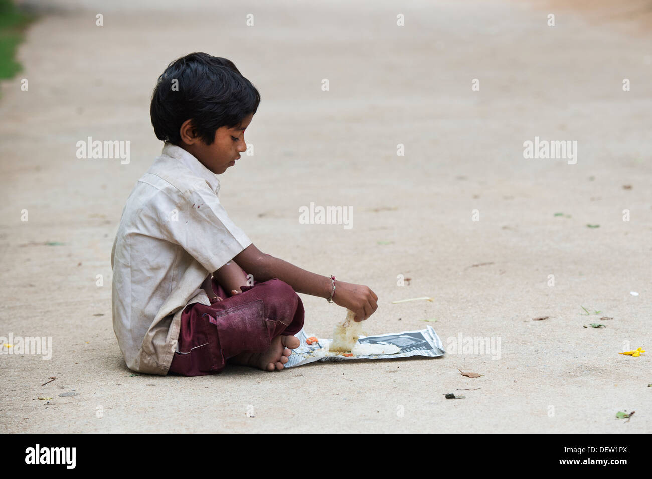 Indiano di casta inferiore boy eating dosa per la colazione su un Indiano street. Andhra Pradesh, India Foto Stock