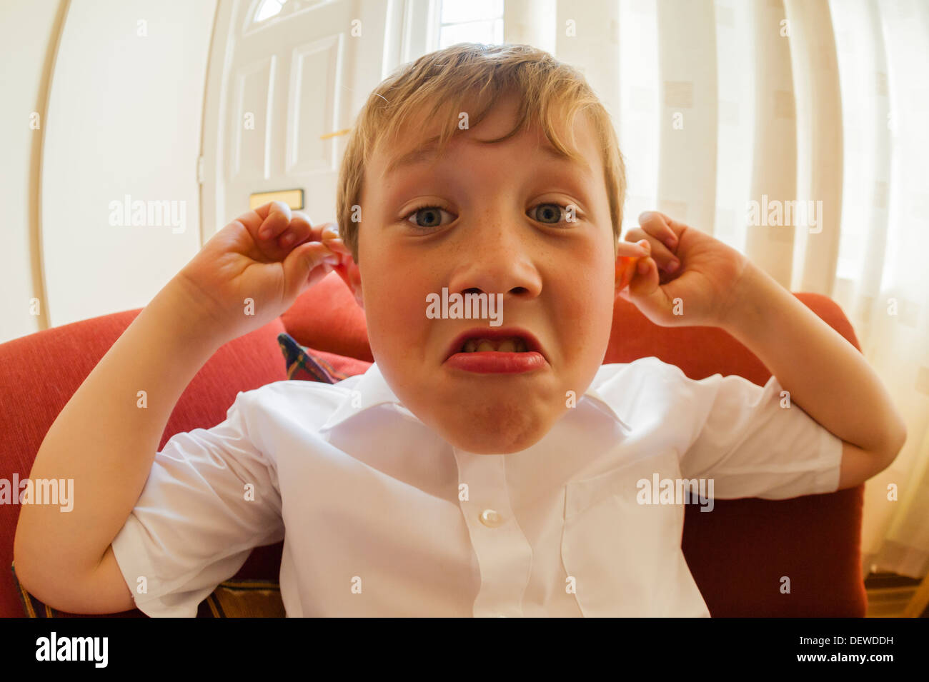 A dieci anni di vecchio ragazzo tirando una divertente volto al chiuso Foto Stock