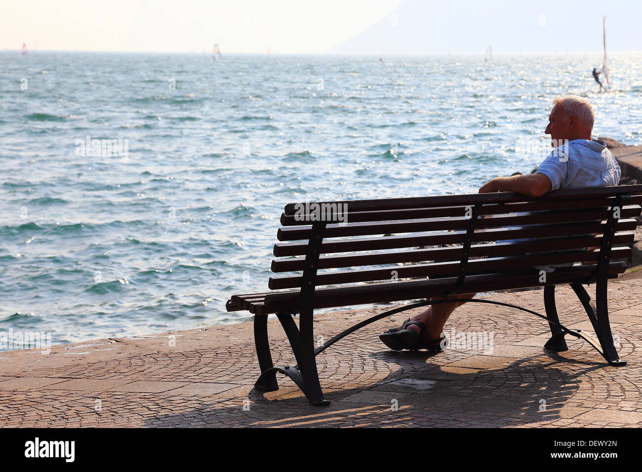 Uomo appoggiato sul banco a Torbole sul lago di Garda, Italia Foto Stock