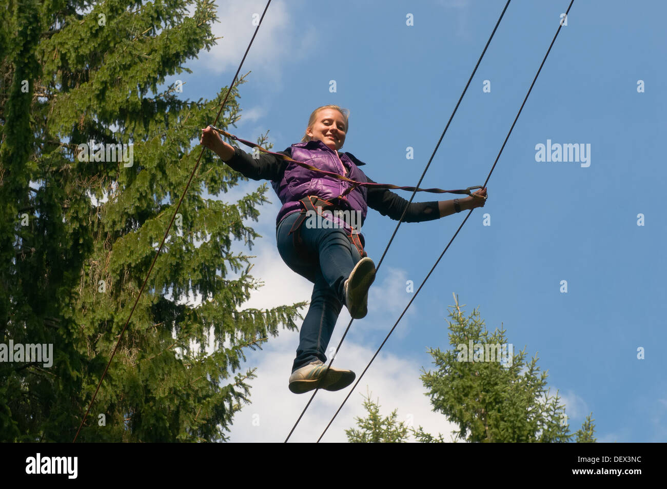 Felice ragazza va su una fune contro il cielo blu Foto Stock