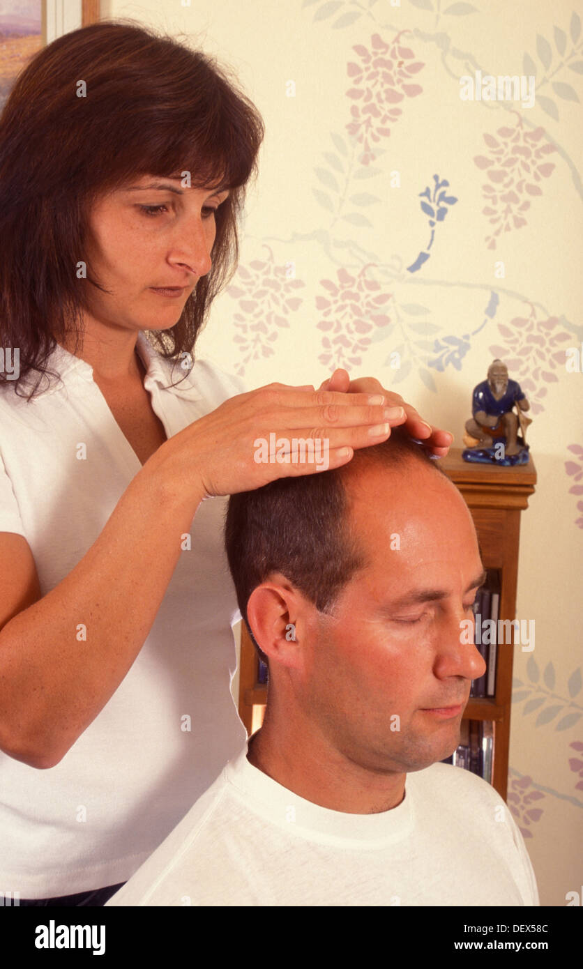 Donna dando reiki guarigione sull uomo da casa Foto Stock