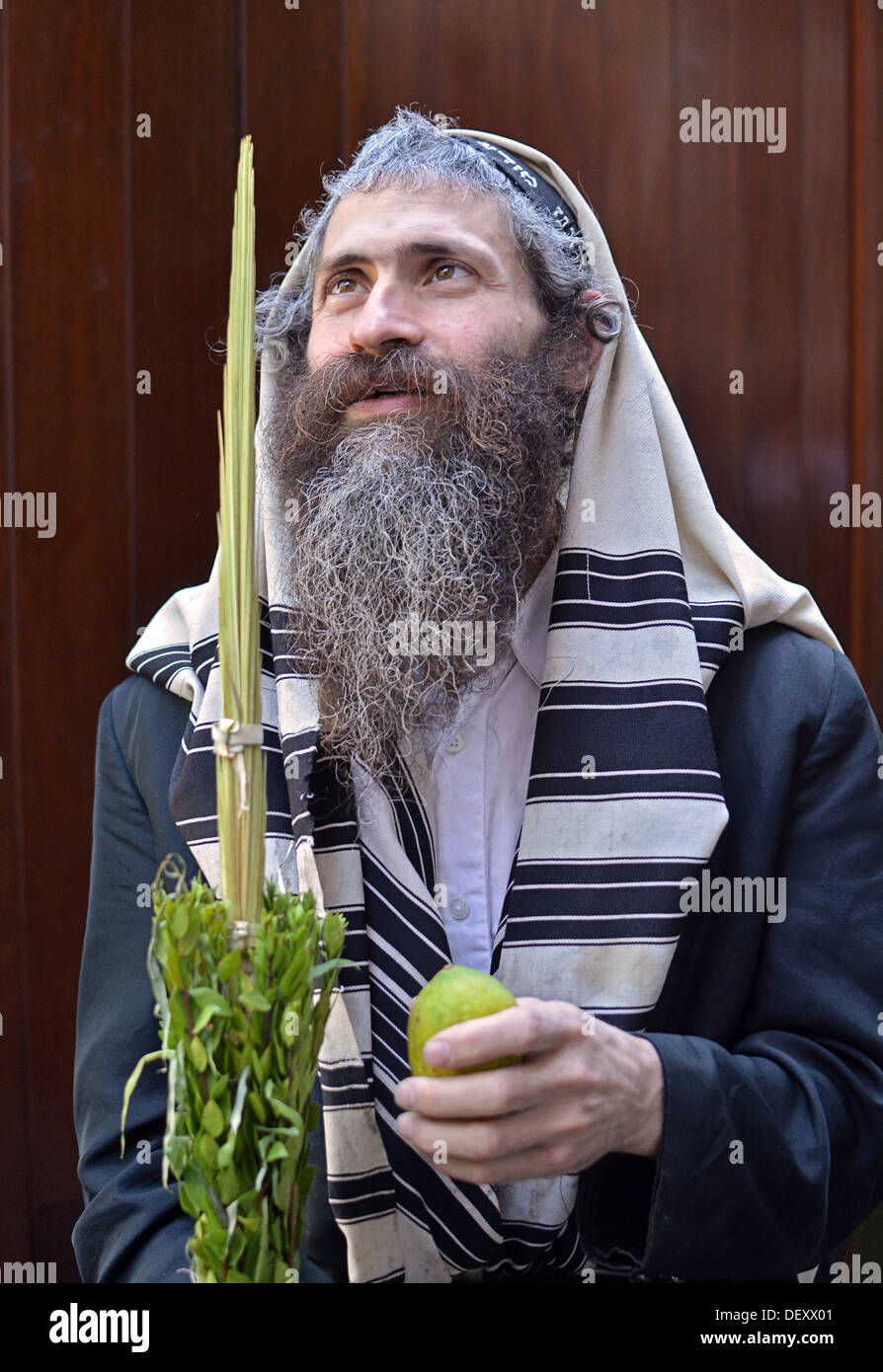 Ritratto di una religiosa ebraica uomo durante Sukkot servizi tenendo un esrog e ispezionando un Lulav. In Crown Heights, Brooklyn NY Foto Stock