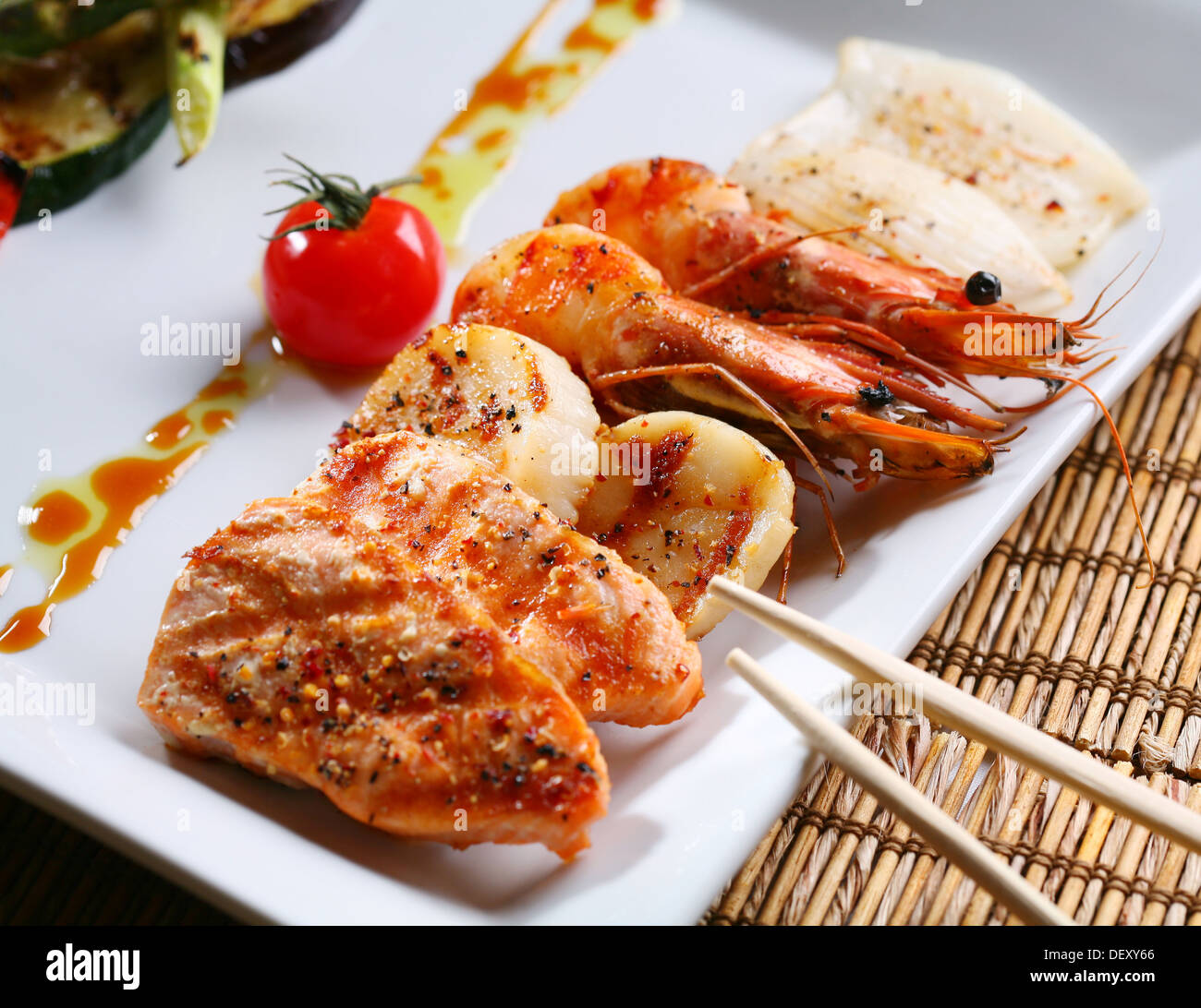 Grigliate di prodotti marini su una piastra bianca con salsa. Foto Stock