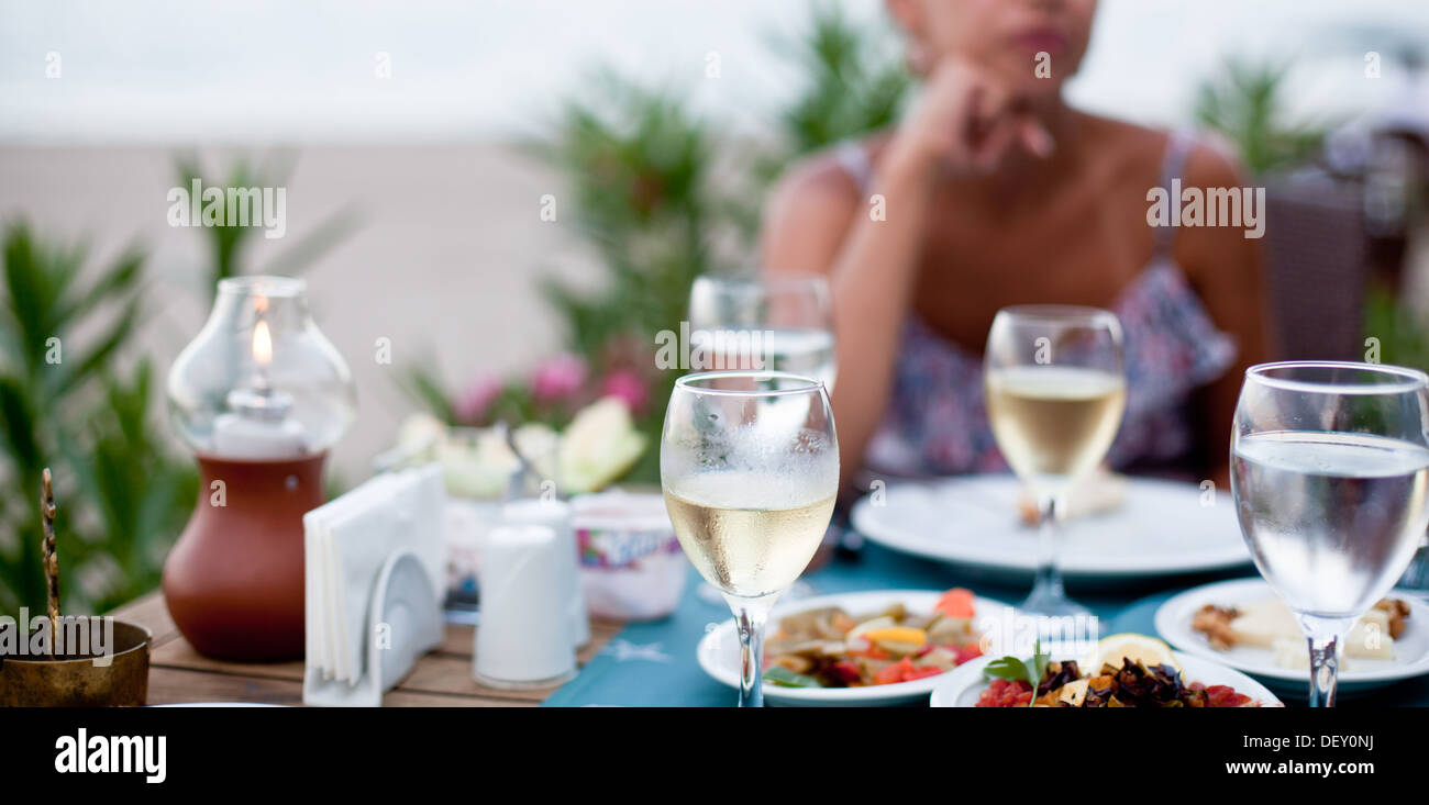 Cena romantica con vino bianco. Sullo sfondo di una ragazza è al di fuori della messa a fuoco. Foto Stock