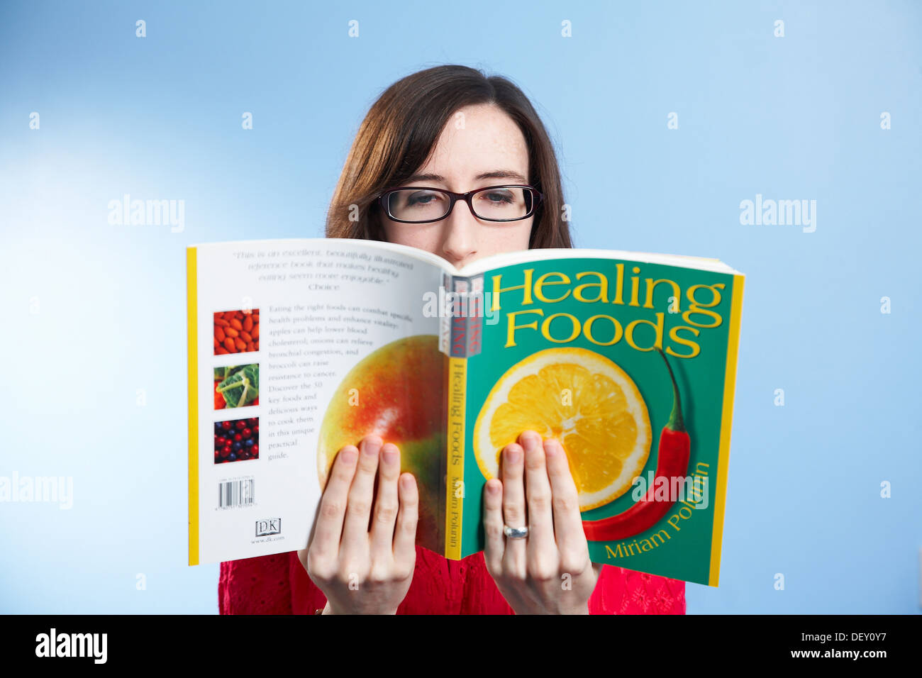 Studio shot di una donna con gli occhiali per leggere un libro. Foto Stock