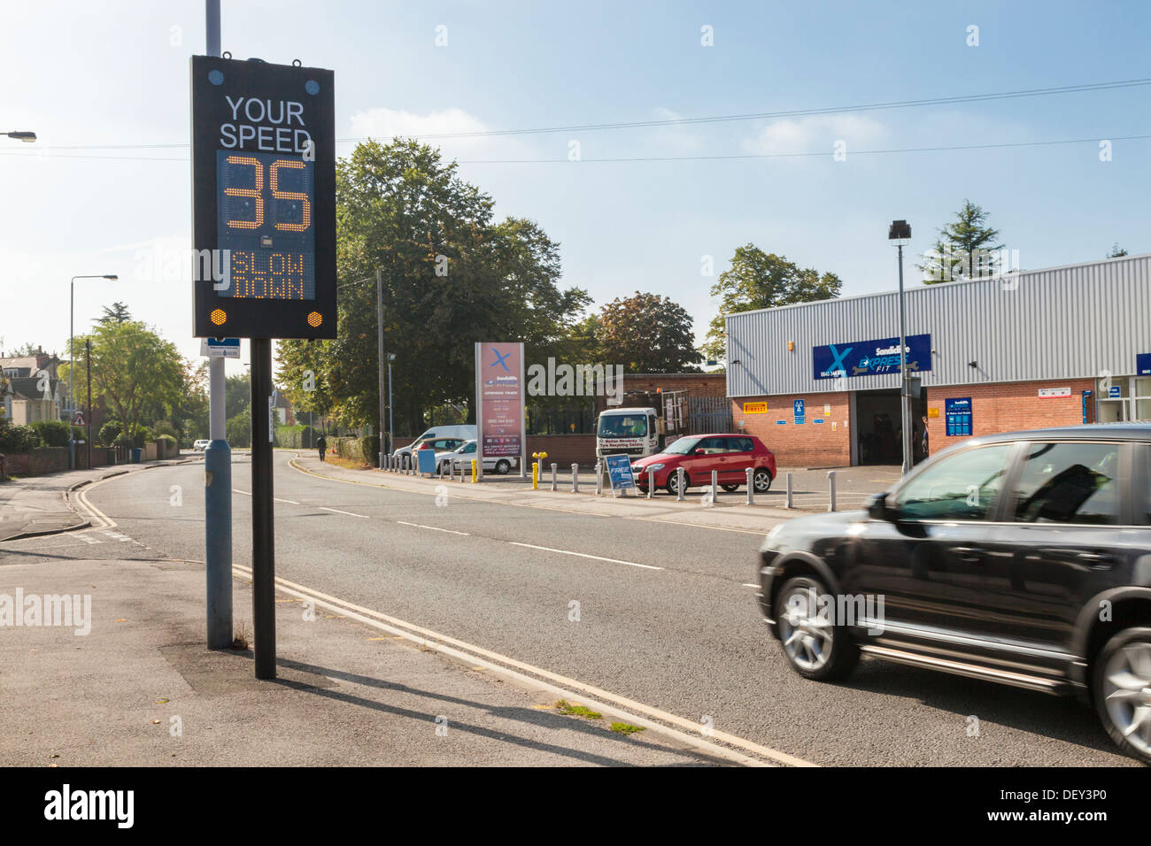Guida troppo veloce, rallentare il segno elettronico. Un accelerando la vettura supera il limite di velocità quando si passa da un regime di traffico spia, England, Regno Unito Foto Stock