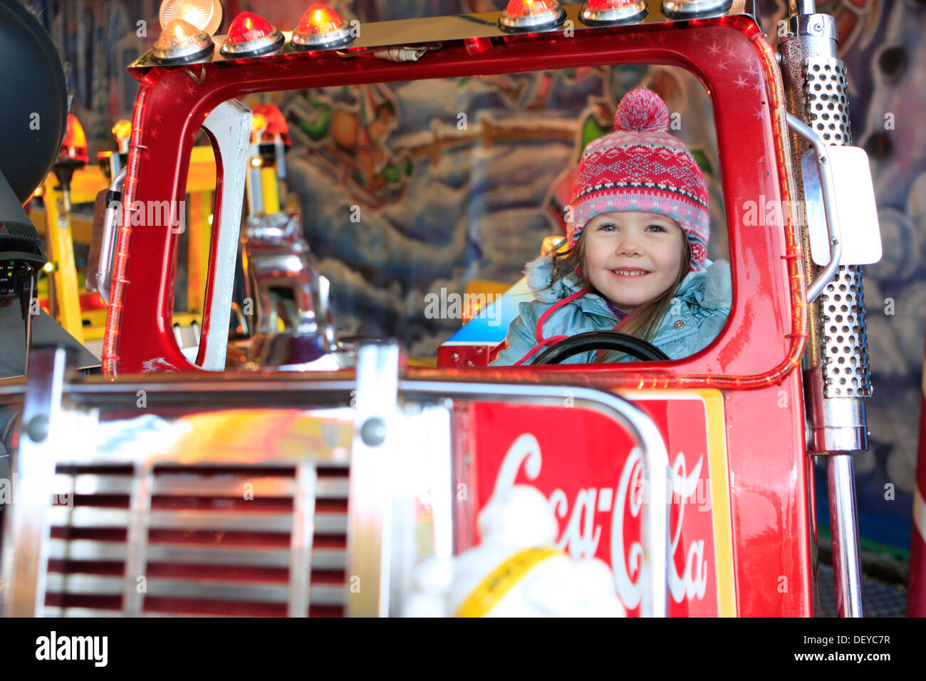 Bambina di tre anni, in sella a un carrello su una giostra a un mercato di Natale Foto Stock