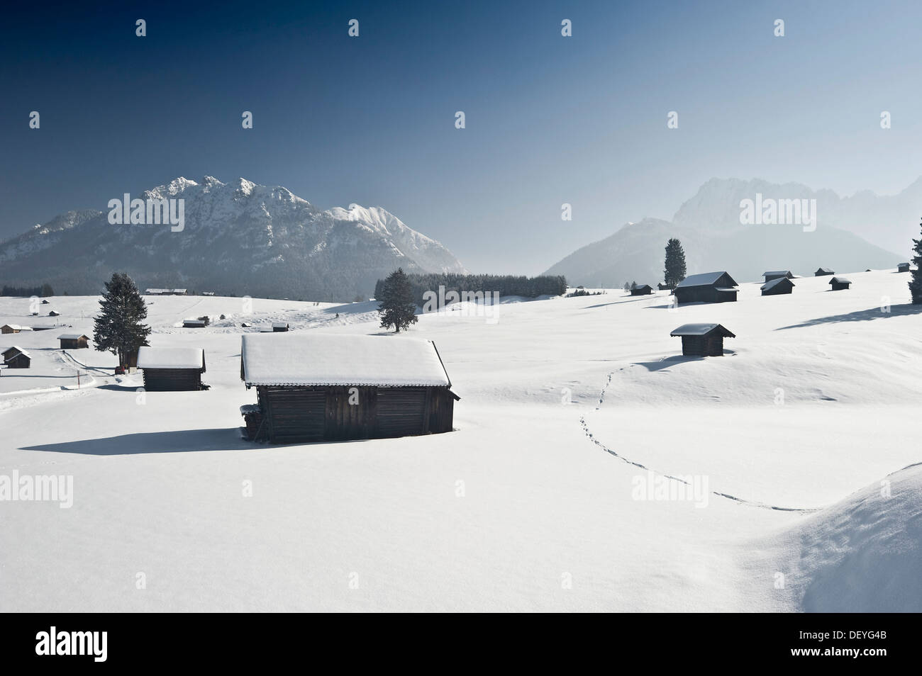 Neve-coperta di pascoli e fienili, gamma Wetterstein sul retro, Mittenwald, Alta Baviera, Baviera, Germania Foto Stock