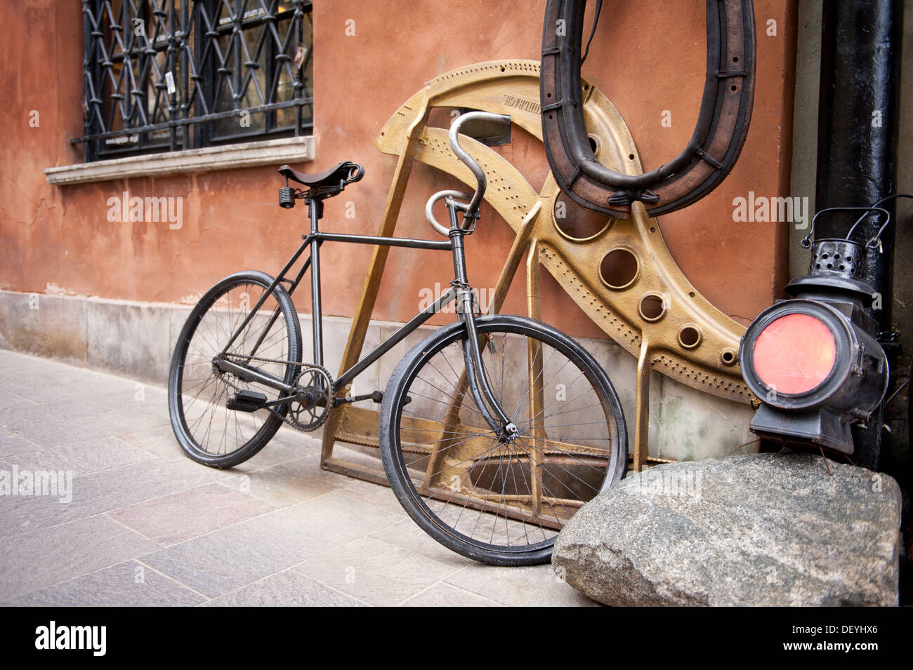Lanterna e vecchio ciclo nero appoggiarsi contro la parete Foto Stock