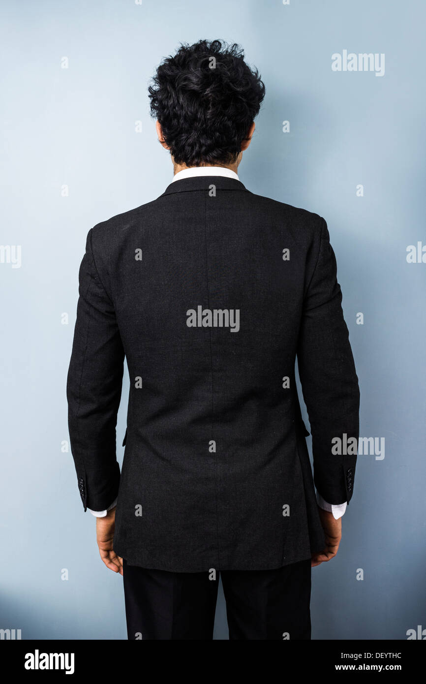 Vista posteriore del giovane multi razziale business man contro una parete blu Foto Stock