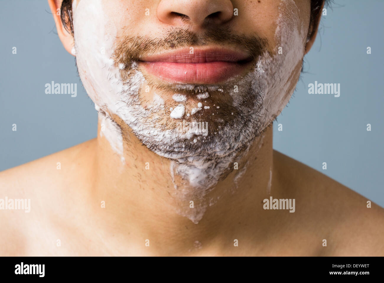 Close up sul mento di un giovane uomo come lui è sempre pronta per la rasatura con schiuma e acqua Foto Stock