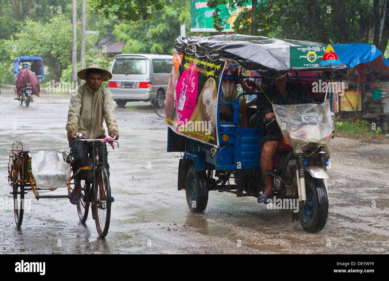 La gente ride sotto la pioggia lungo la strada principale di Sittwe, Birmania. Foto Stock