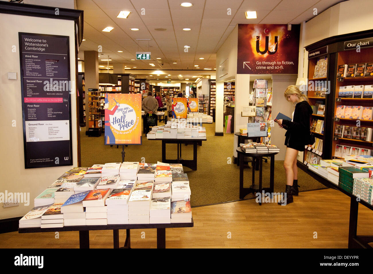 Waterstones bookstore; una giovane donna che acquista all'interno della libreria Waterstones, Cambridge UK Foto Stock