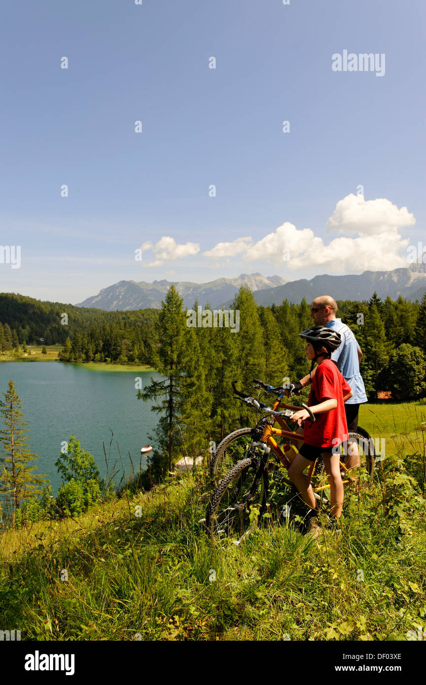 Gita in bicicletta con la mountain bike, il padre e il figlio di fronte al lago Lautersee, Mittenwald, montagne Karwendel, Werdenfelser Land Foto Stock