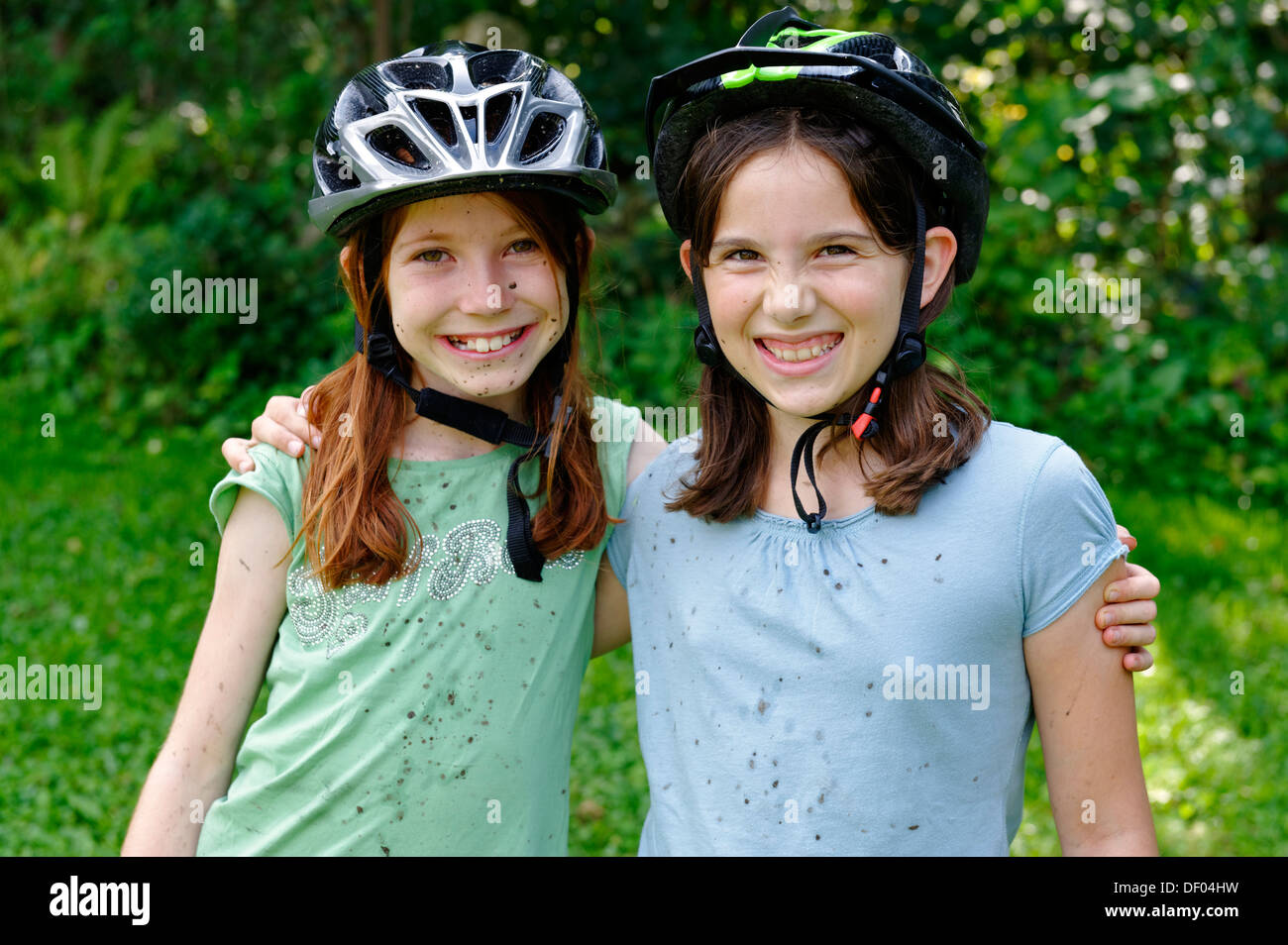 Le ragazze che indossano caschi ciclo coagulato con fango dopo un tour in mountain bike Foto Stock