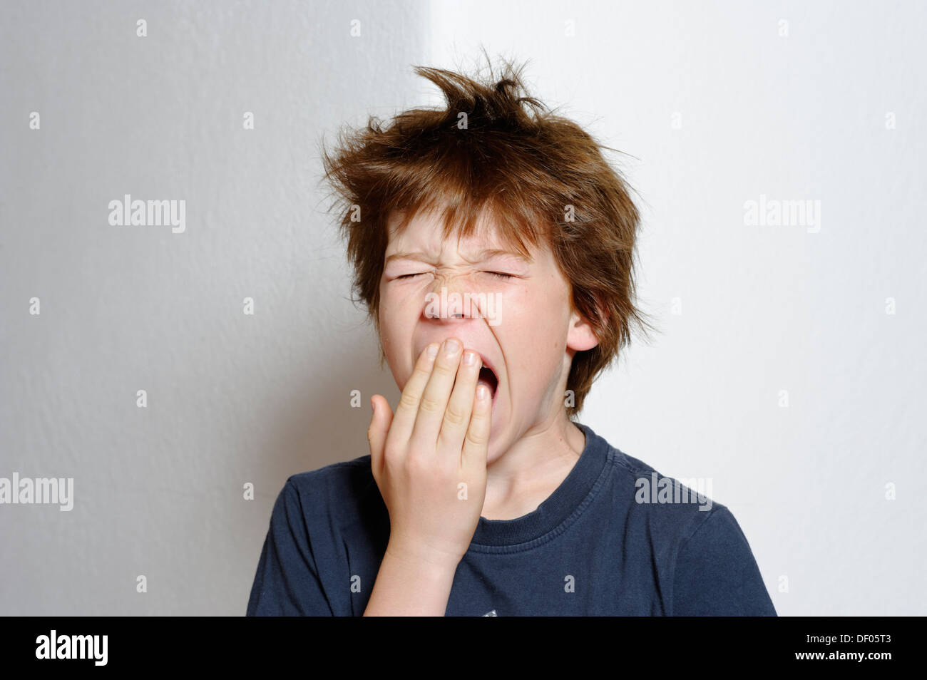 Il ragazzo, 12 anni, sbadigli, con capelli tousled Foto Stock
